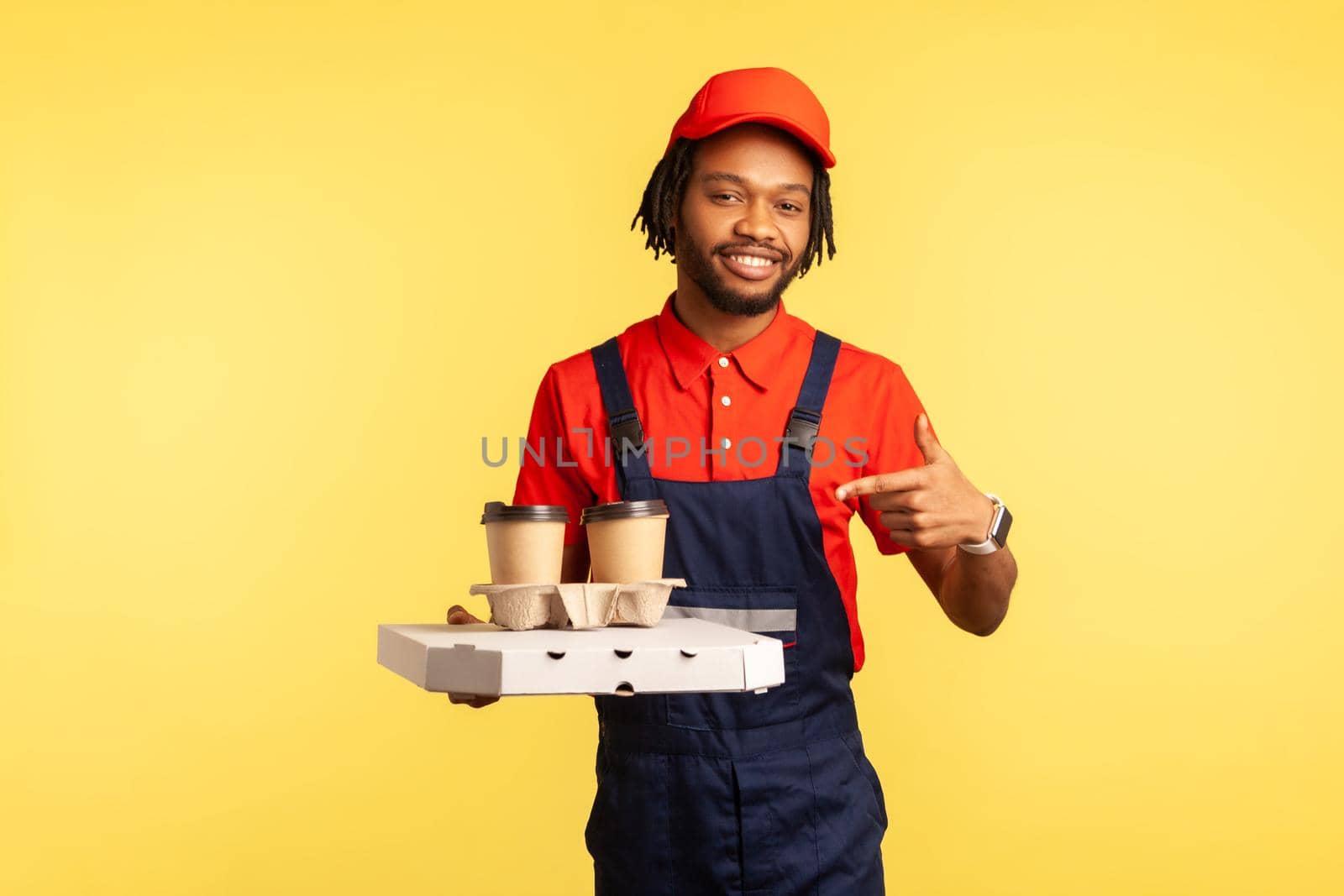 Optimistic courier man in blue overalls pointing at coffee and box with fast food. by Khosro1