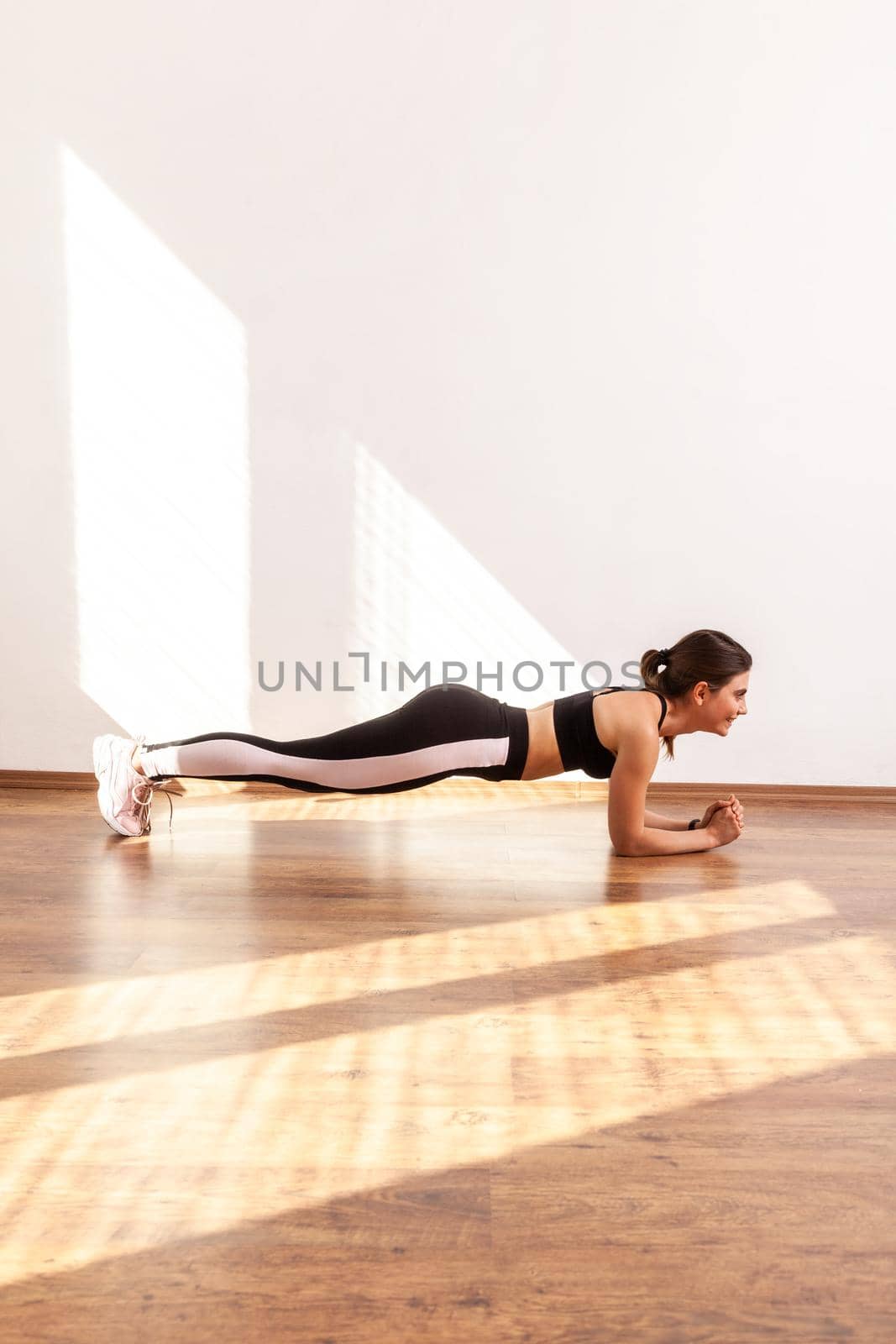Side view of slim athletic woman doing sports exercises doing plank exercising abdominal muscles by Khosro1