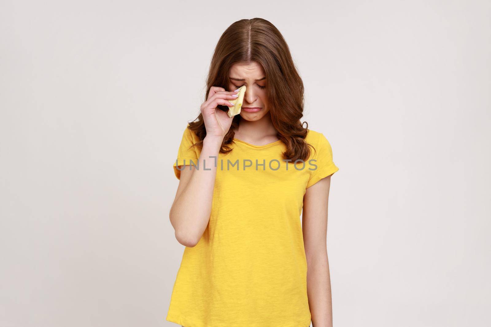 Portrait of upset teenager girl frowning, wiping tears crying with handkerchief, feeling desperate hopeless, coping lonely in emotional stress. Indoor studio shot isolated on gray background.