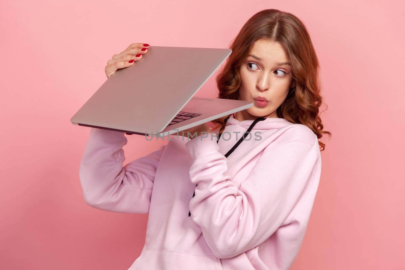 Portrait of curious curly haired teenage girl in hoodie peeping at laptop screen, shocked web content by Khosro1