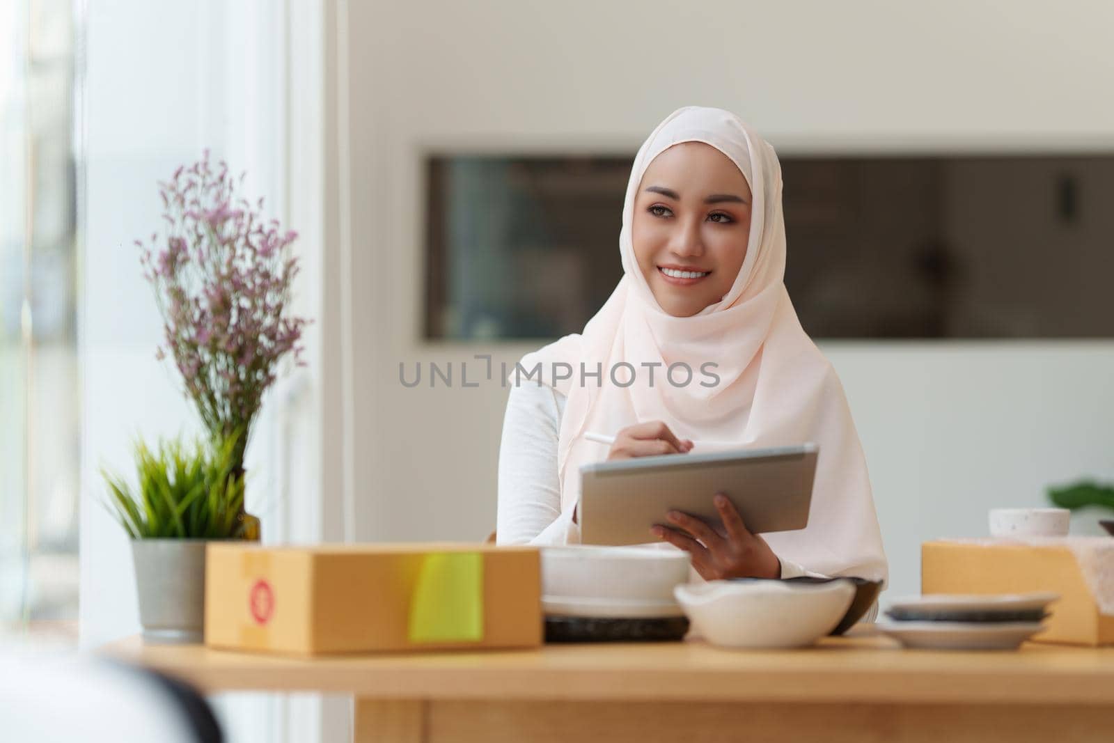 Image of Young asian woman startup freelance with parcel box and talking with customer by computer laptop. Online marketing packing box delivery concept