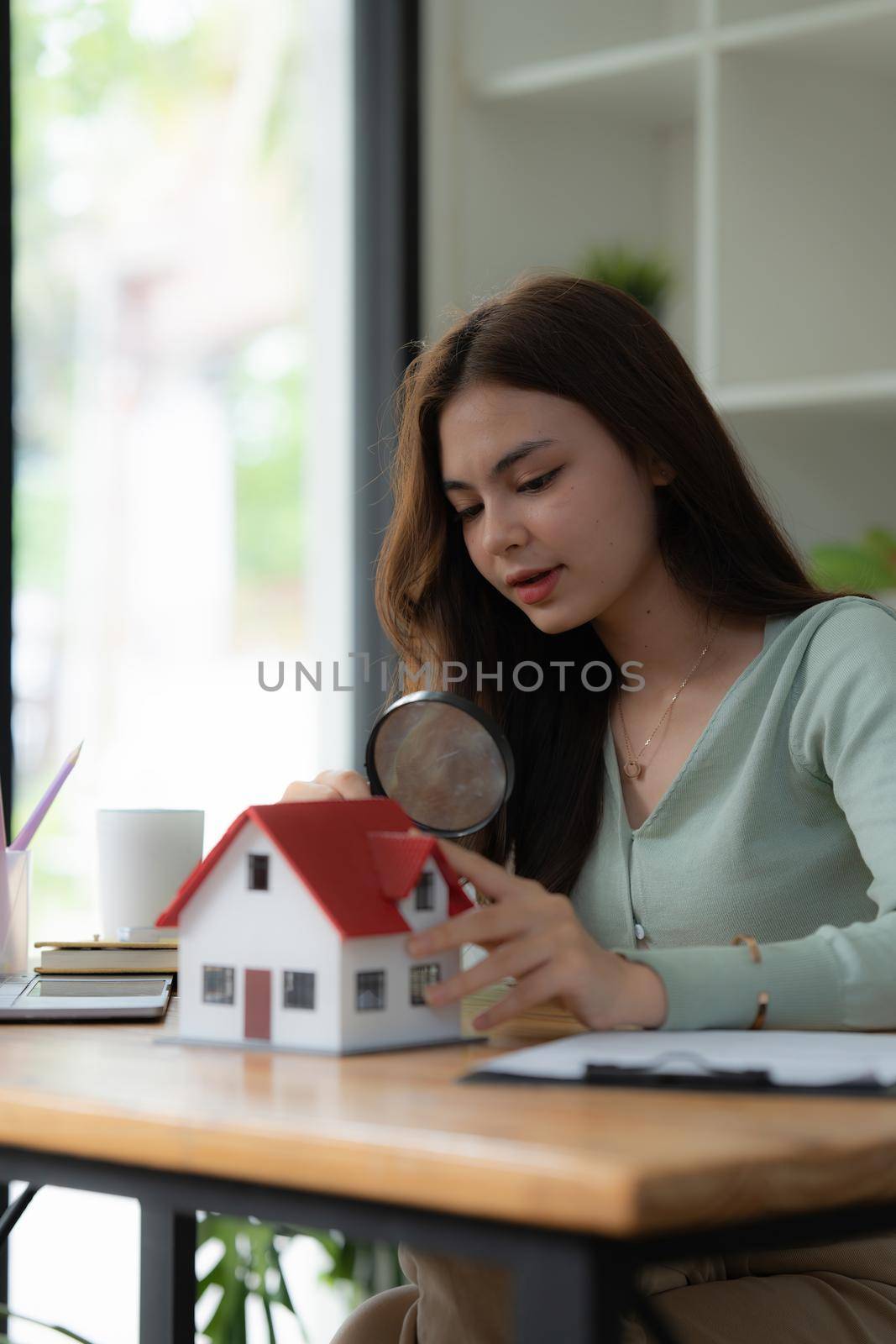 A woman holding magnifying glass and checking house model .Real Estate House Appraisal And Inspection concept