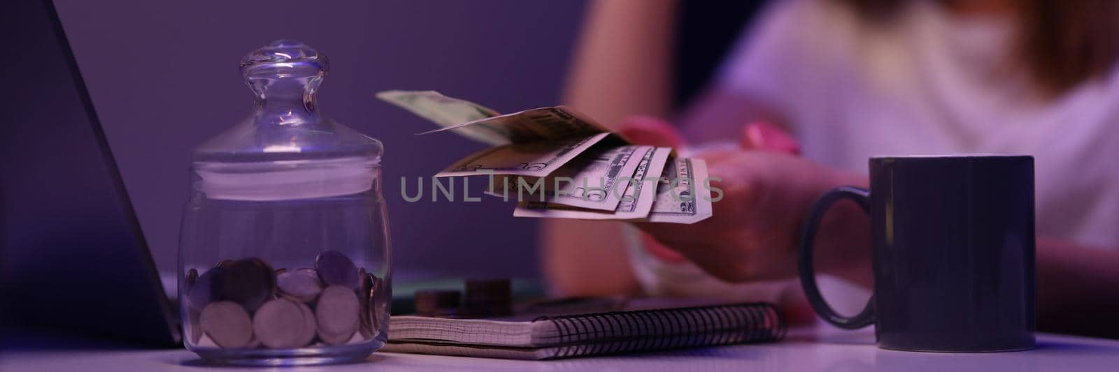 Close-up of broken young woman counting cash money, glass container with coins on desk . Saving up for tomorrow, pay bills. Finance, family budget concept