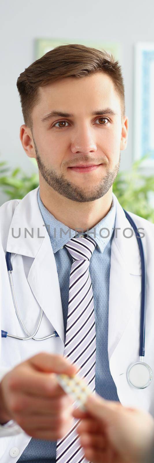 Male doctor in uniform give tablets in blister to patient by kuprevich