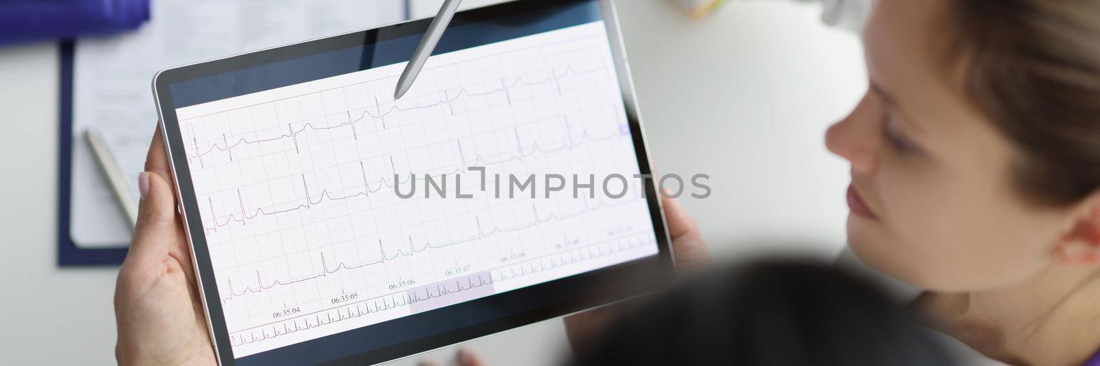 Doctor show digital tablet screen with heart cardiogram result to coworker by kuprevich