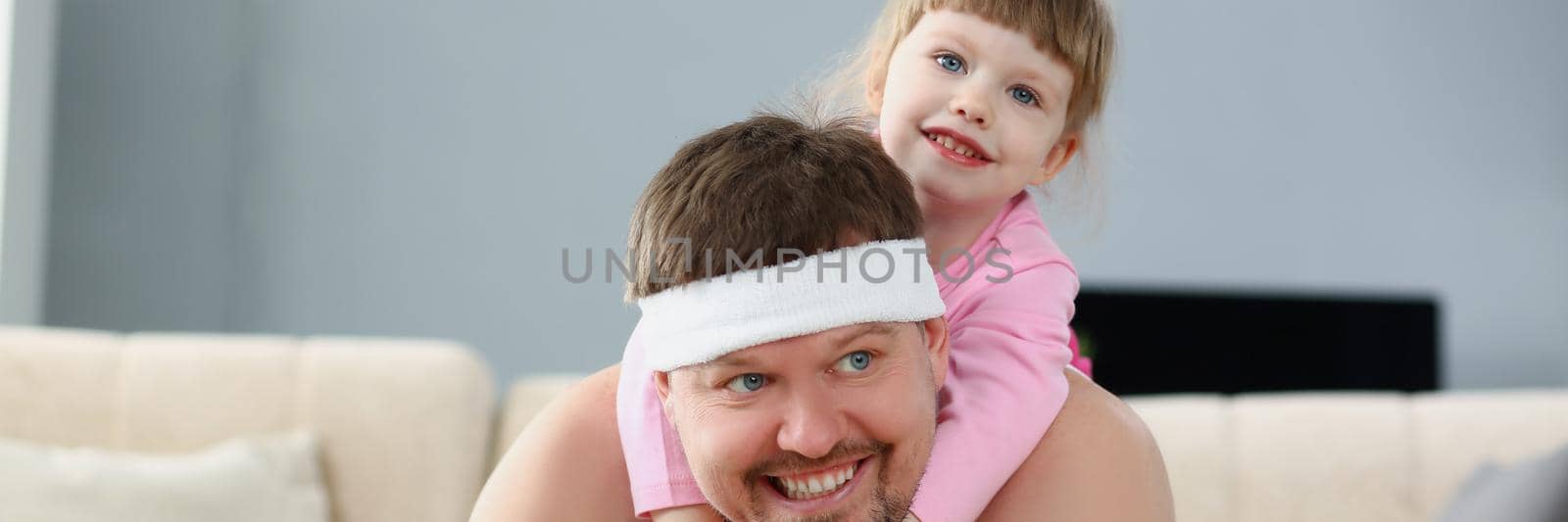 Portrait of father and daughter spend time at home, sport activity with child on back. Kid spend quality time with parent. Childhood, parenthood concept