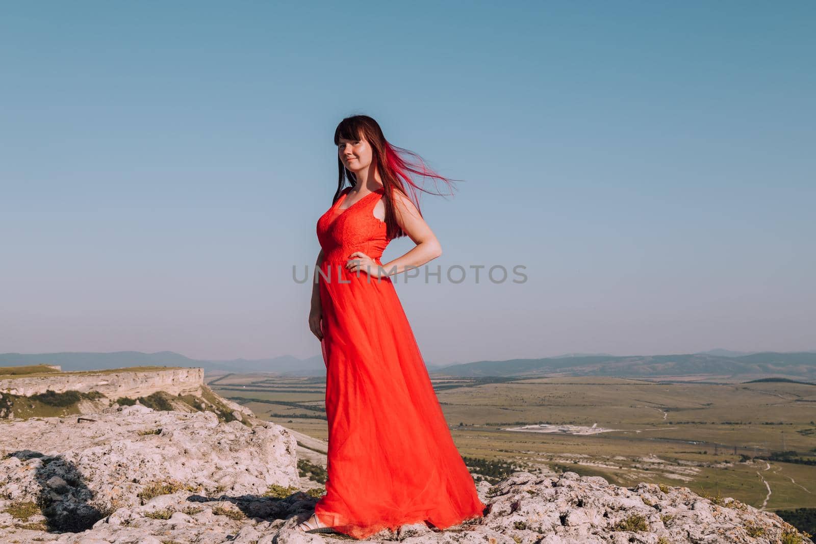A girl in a red dress on the background of the mountains lifestyle. Illustrating articles about travel. A girl with a beautiful view. Vacation in Crimea. White rock. View of the villages. Lifestyle processing. Copy space .