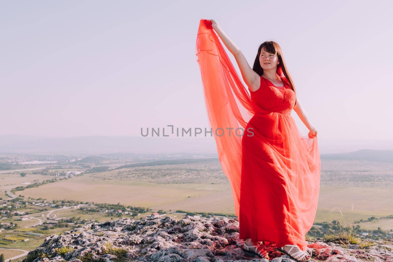 A girl in a red dress on the background of the mountains lifestyle. Illustrating articles about travel. A girl with a beautiful view. Vacation in Crimea. White rock. View of the villages. Lifestyle processing. Copy space .