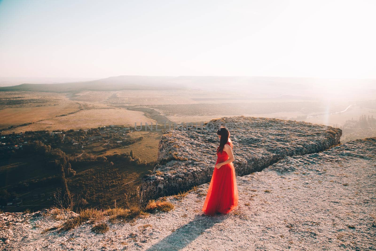 A girl in a red dress on the background of the mountains lifestyle. Illustrating articles about travel. A girl with a beautiful view. Vacation in Crimea. White rock. View of the villages. Lifestyle processing. Copy space .