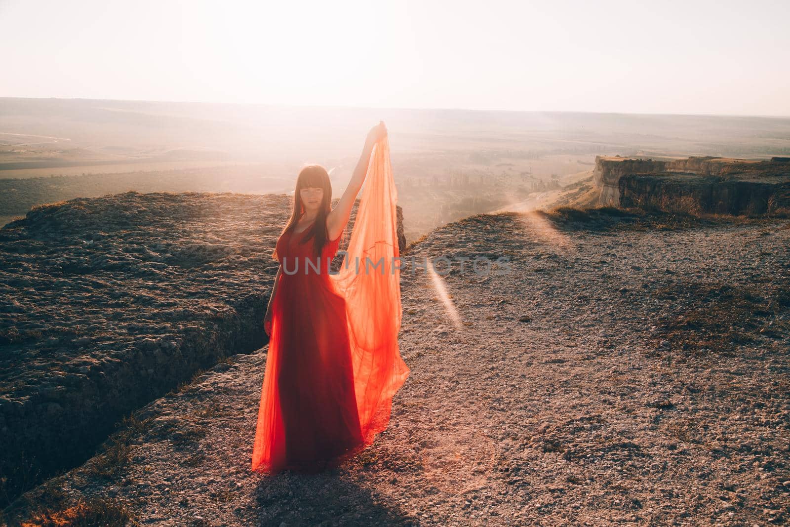 A girl in a red dress on the background of the mountains lifestyle. Illustrating articles about travel. A girl with a beautiful view. Vacation in Crimea. White rock. View of the villages. Lifestyle processing. Copy space .