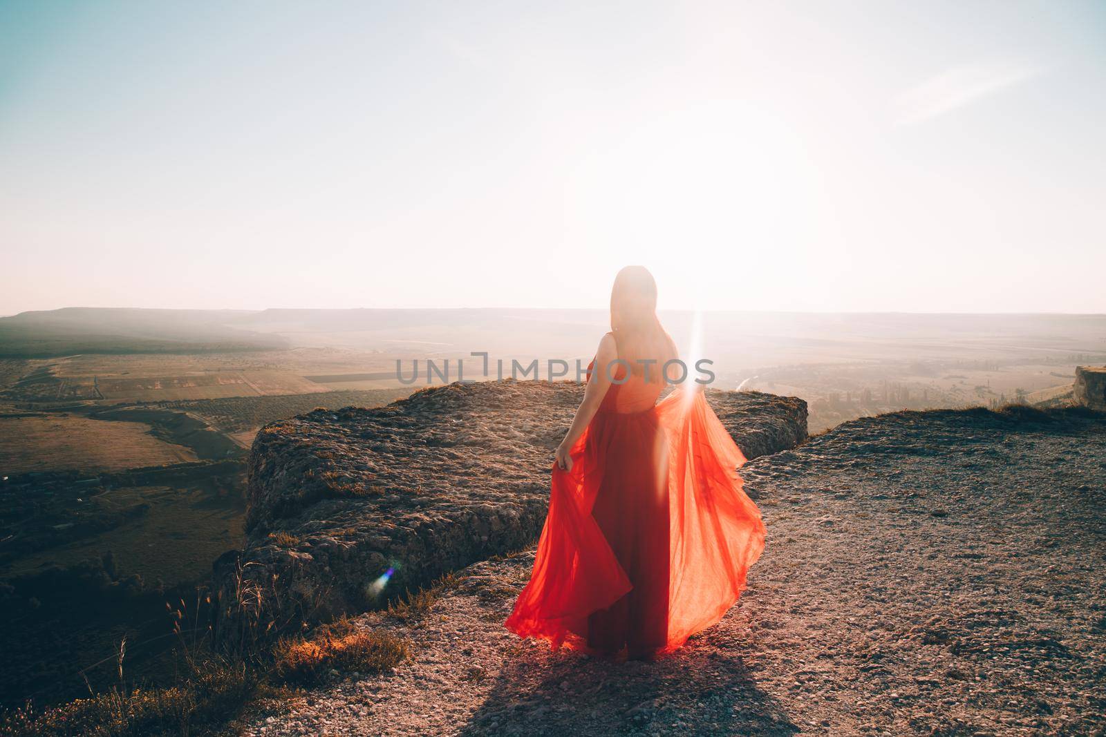 A girl in a red dress on the background of the mountains lifestyle. Illustrating articles about travel. A girl with a beautiful view. Vacation in Crimea. White rock. View of the villages. Lifestyle processing. Copy space .