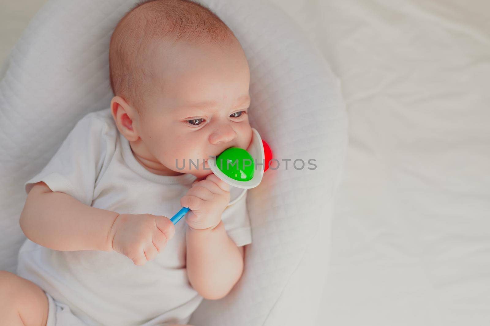 The kid is gnawing on a lifestyle rattle . Children's toys. An article about children. An article about children's toys. An article about teething. by alenka2194