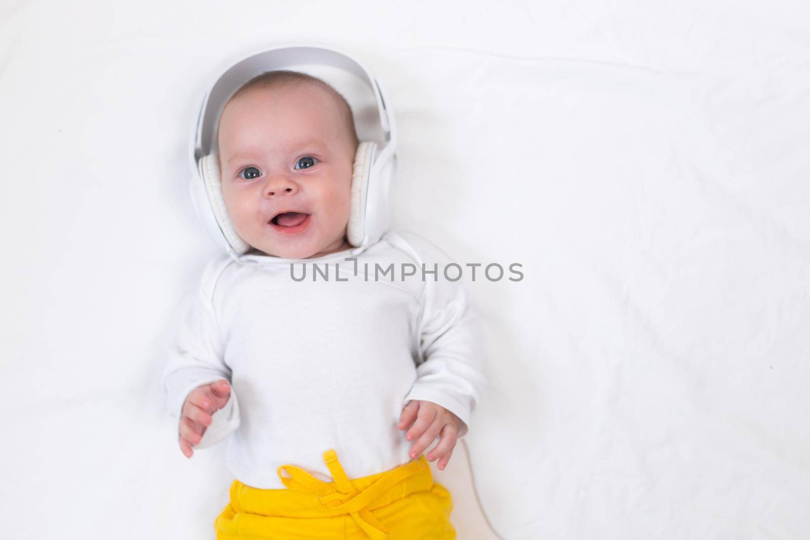 The kid listens to music with headphones on a white background. An article about children. Music for children. The benefits of classical music for children. Article about headphones. The choice of headphones. Copy Space