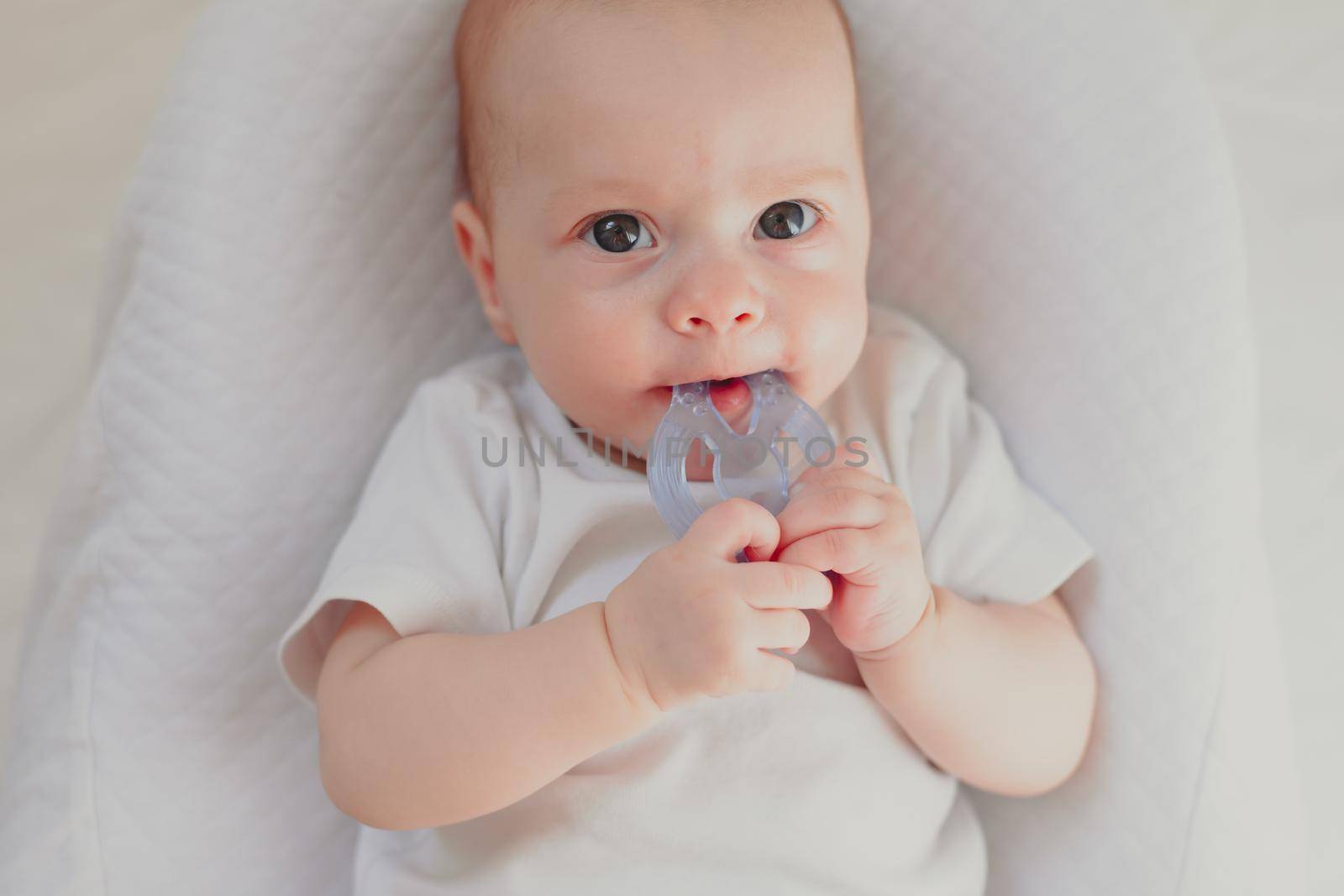 The kid is gnawing on a lifestyle rattle . Children's toys. An article about children. An article about children's toys. An article about teething. by alenka2194