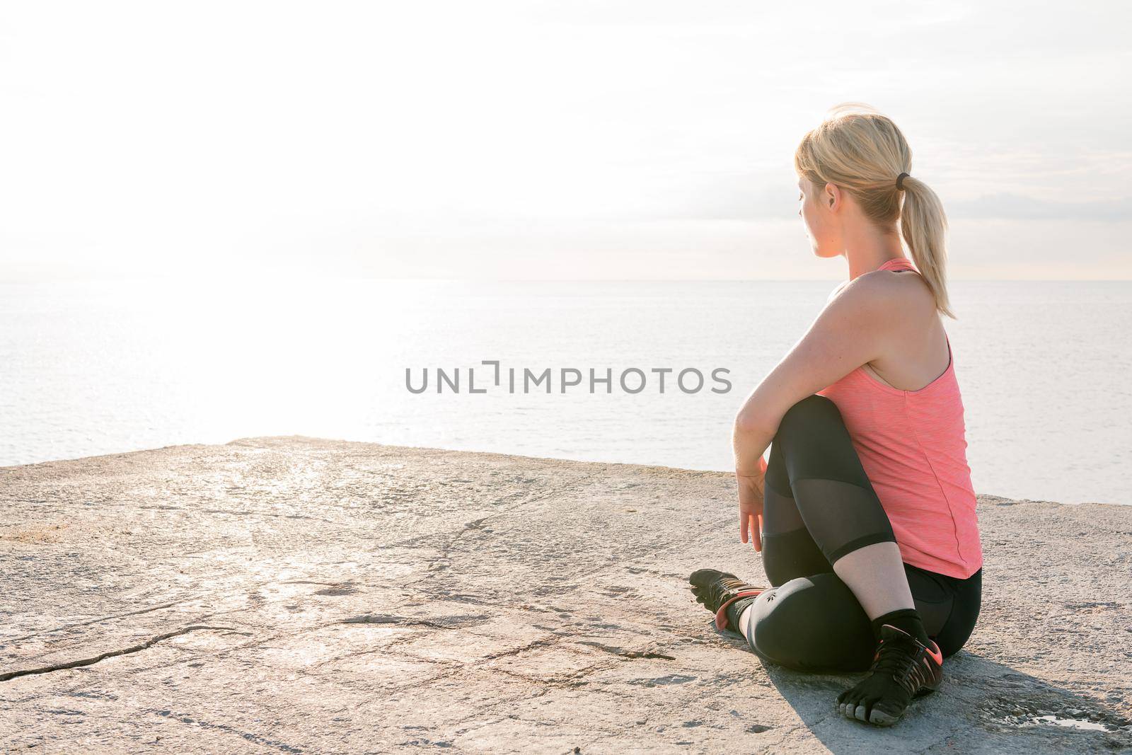 beautiful blonde woman practices yoga stretching at dawn sitting in front of the sea, concept of mental health and relaxation, copy space for text