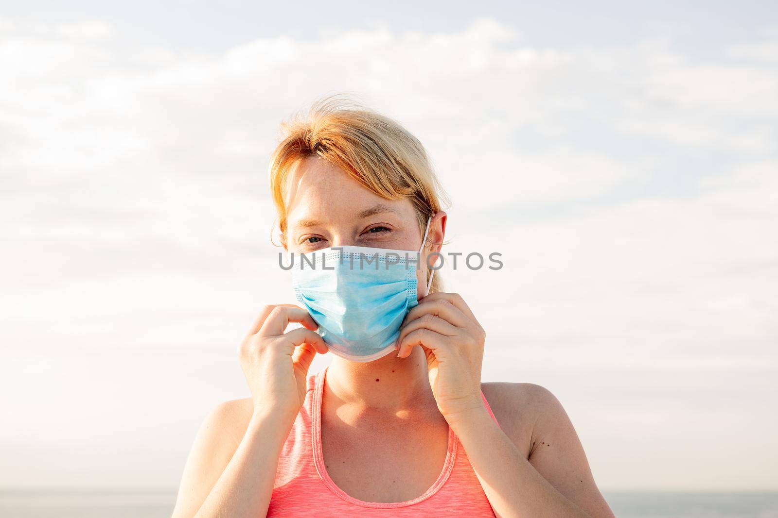 portrait of a beautiful blonde woman wearing a protective mask with the sky in the background, concept of prevention and health care, copy space for text