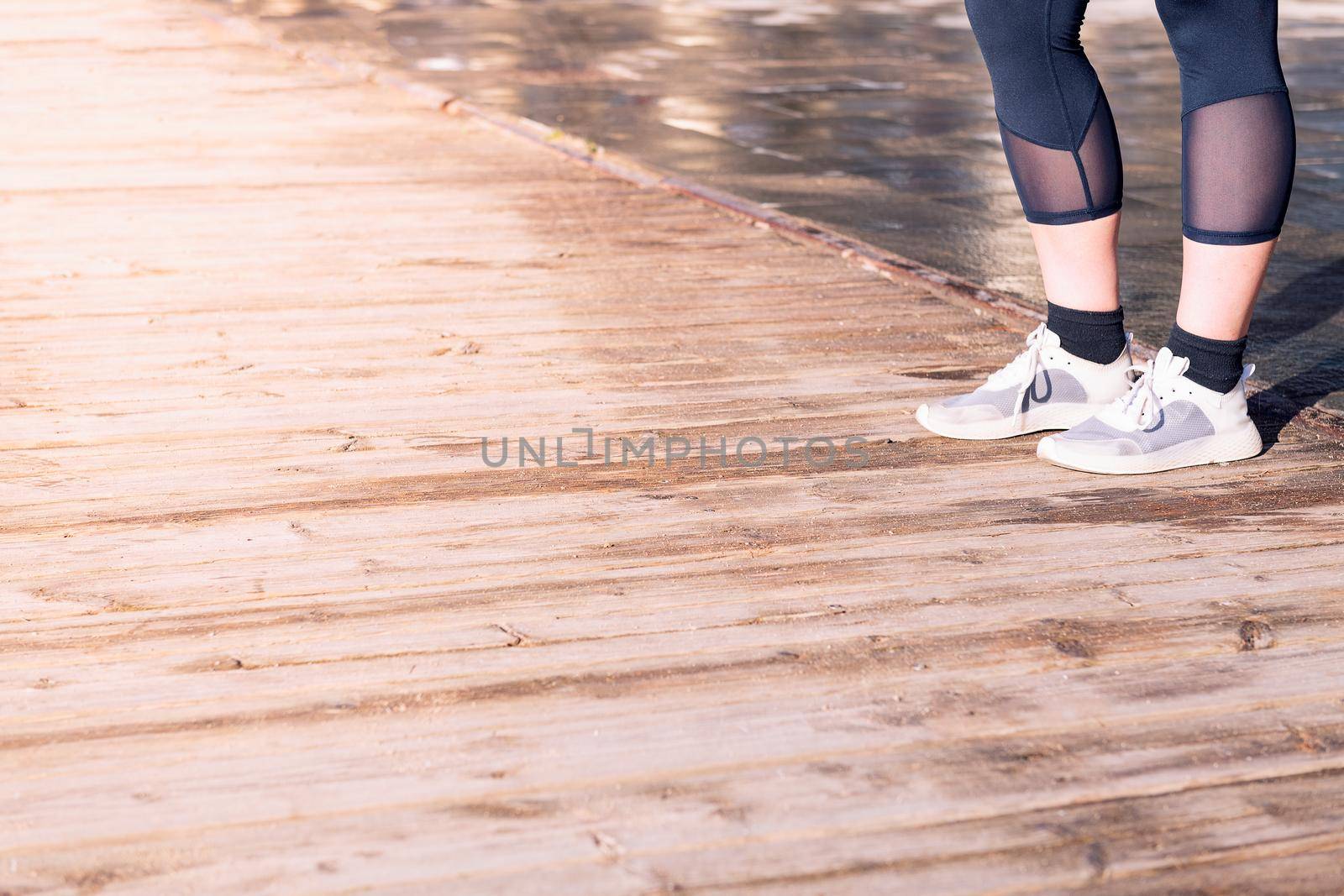 unrecognizable female runner legs ready with running shoes on a wooden floor, sport concept and healthy lifestyle, copy space for text