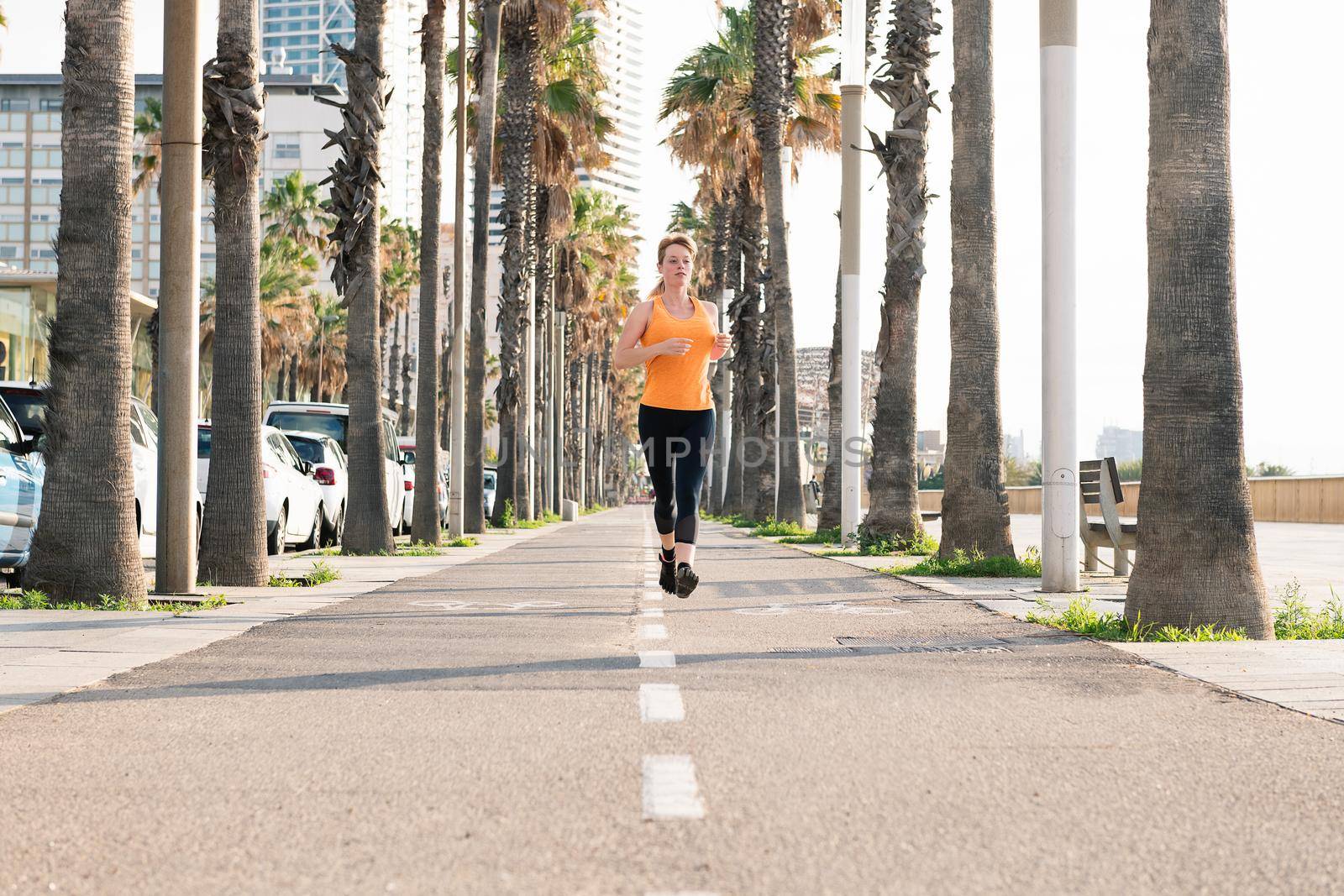 attractive blonde young woman running along the city promenade, sport concept and healthy lifestyle