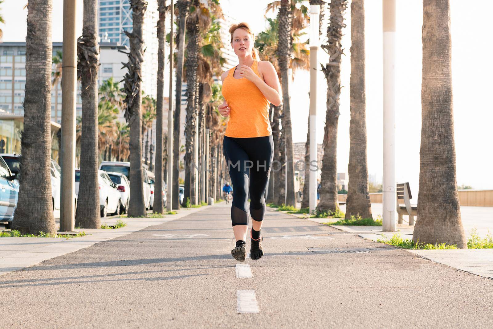 attractive caucasian girl running along the city promenade, sport concept and healthy lifestyle