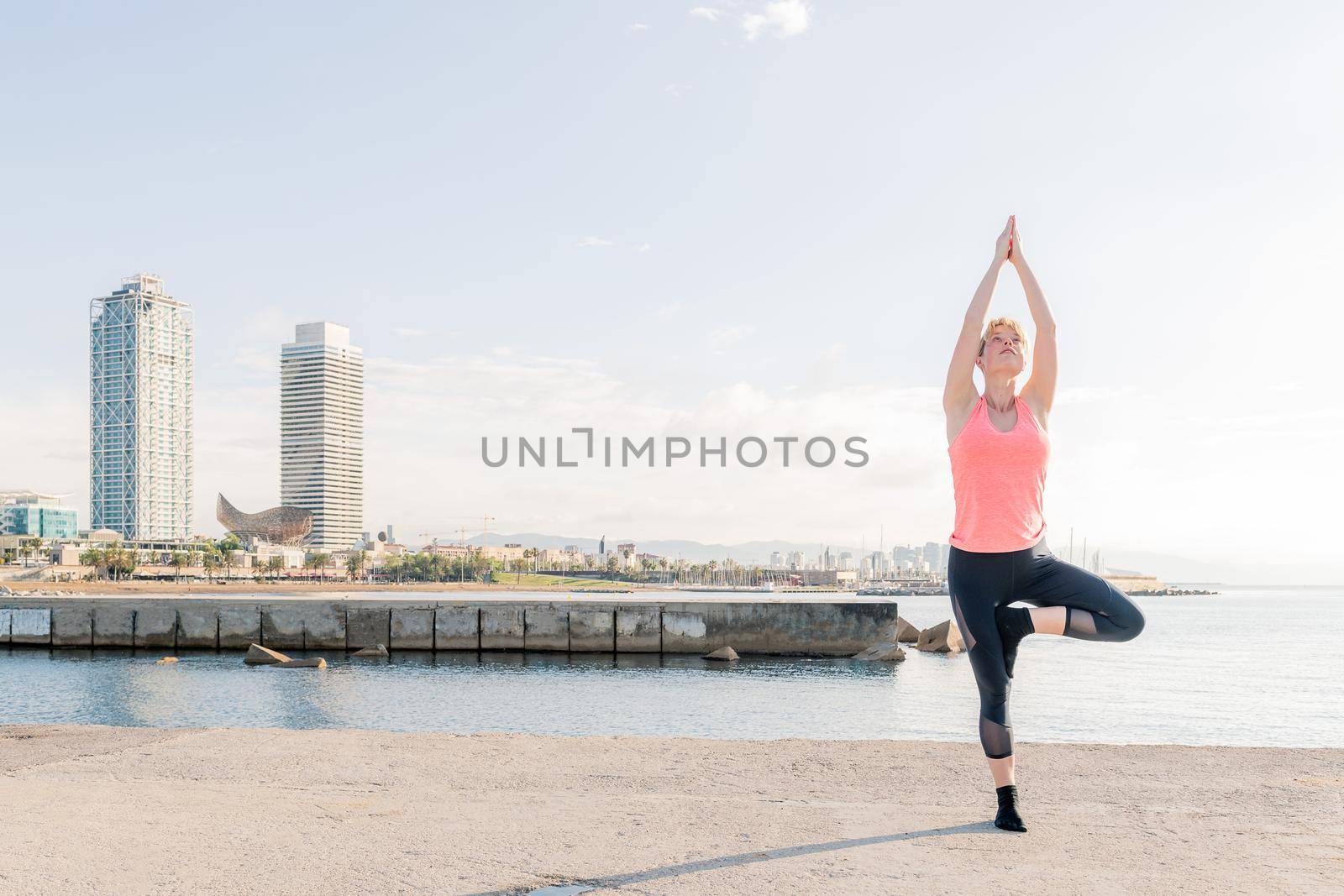 blonde woman practicing yoga at sunrise in front of the sea, mental health care and relaxation concept, text copy