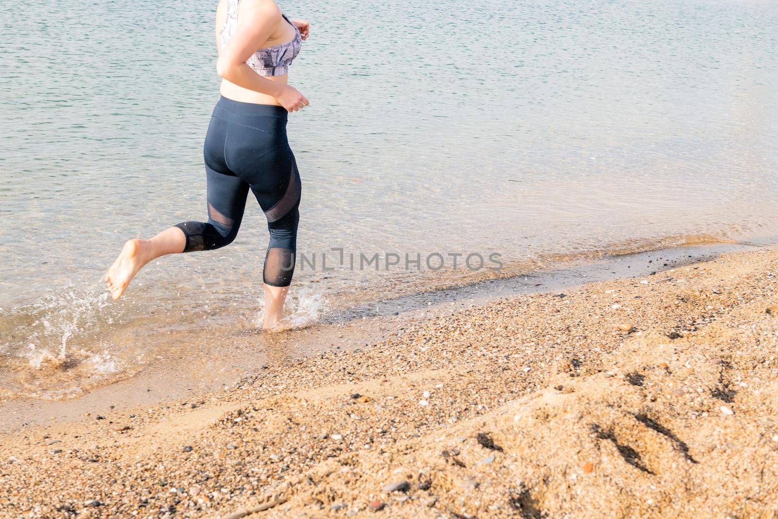 unrecognizable sportswoman running along the beach, healthy lifestyle and sports concept, text copy space