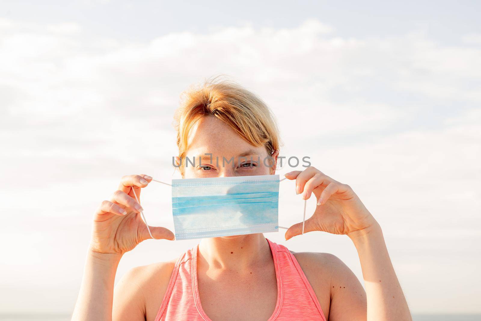 portrait of a beautiful blonde woman with a protective mask with the sky in the background, concept of prevention and health care, copy space for text