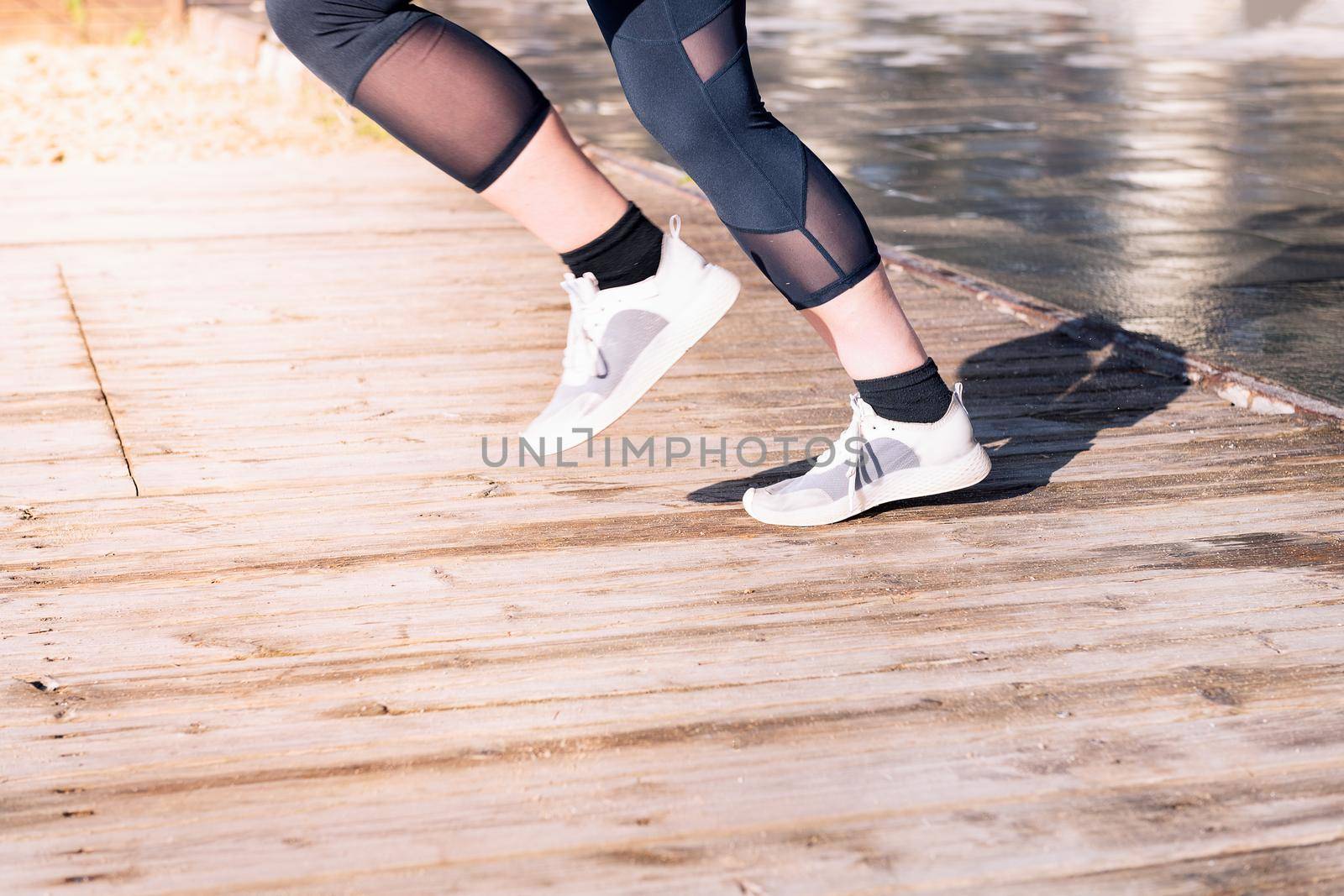 unrecognizable female runner legs jogging in running shoes on a wooden floor, sport concept and healthy lifestyle, copy space for text
