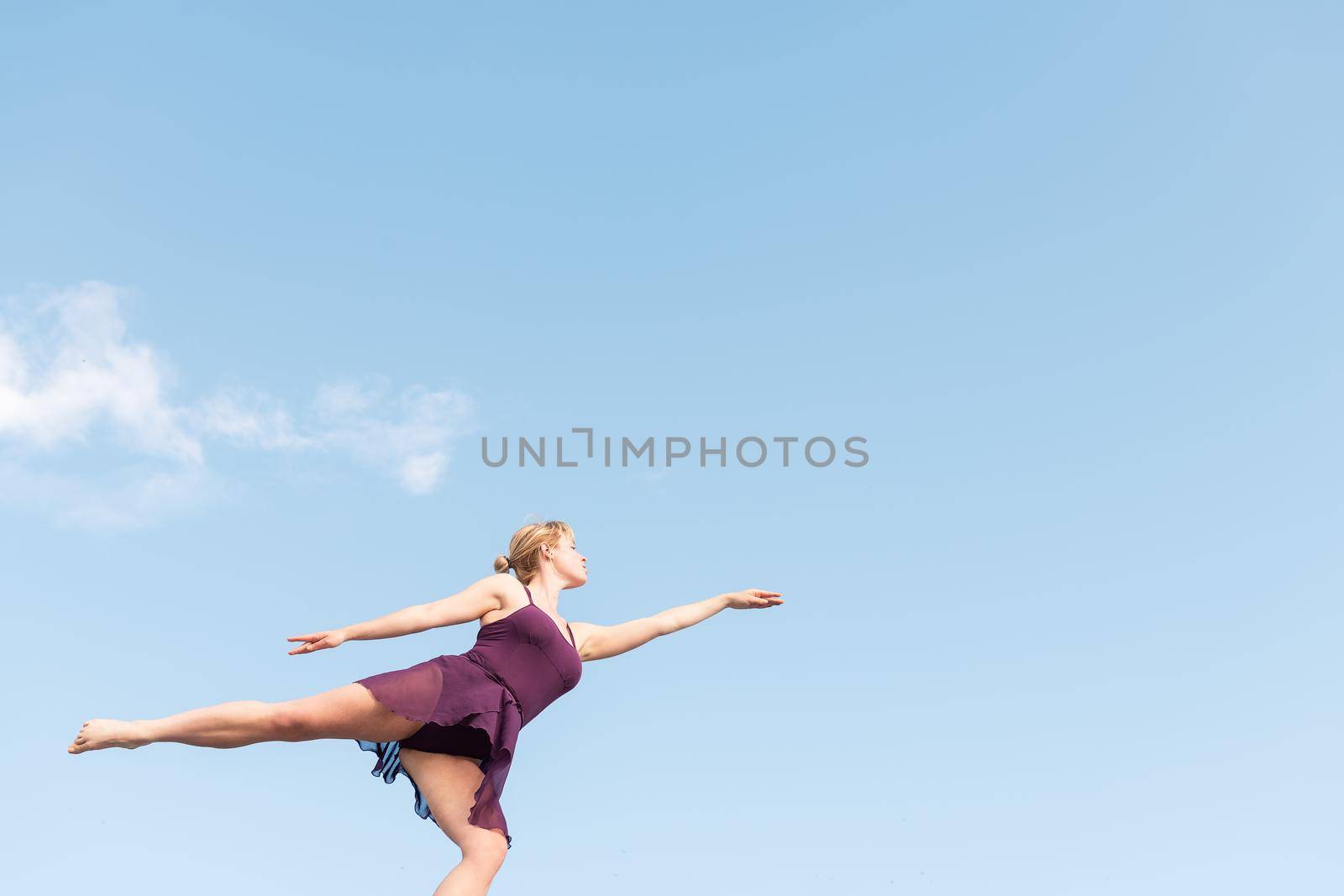 young blonde ballet dancer dancing with the sky in the background, concept of freedom and dance, copy space for text