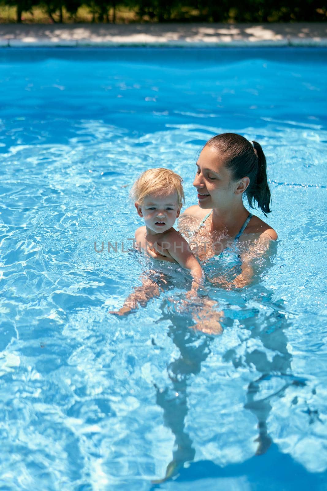 Mom with a small baby in the pool by Nadtochiy