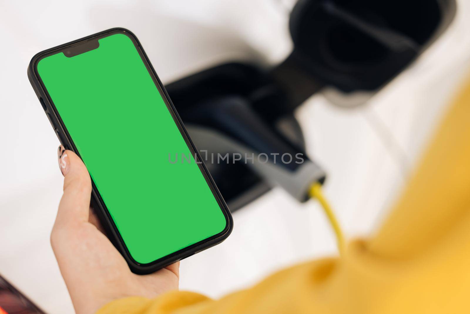 Close up green screen mock up chroma key on mobile phone. EV charging station for electric car with mobile app. Female charges batteries uses phone with chromakey display for activates start charging by uflypro
