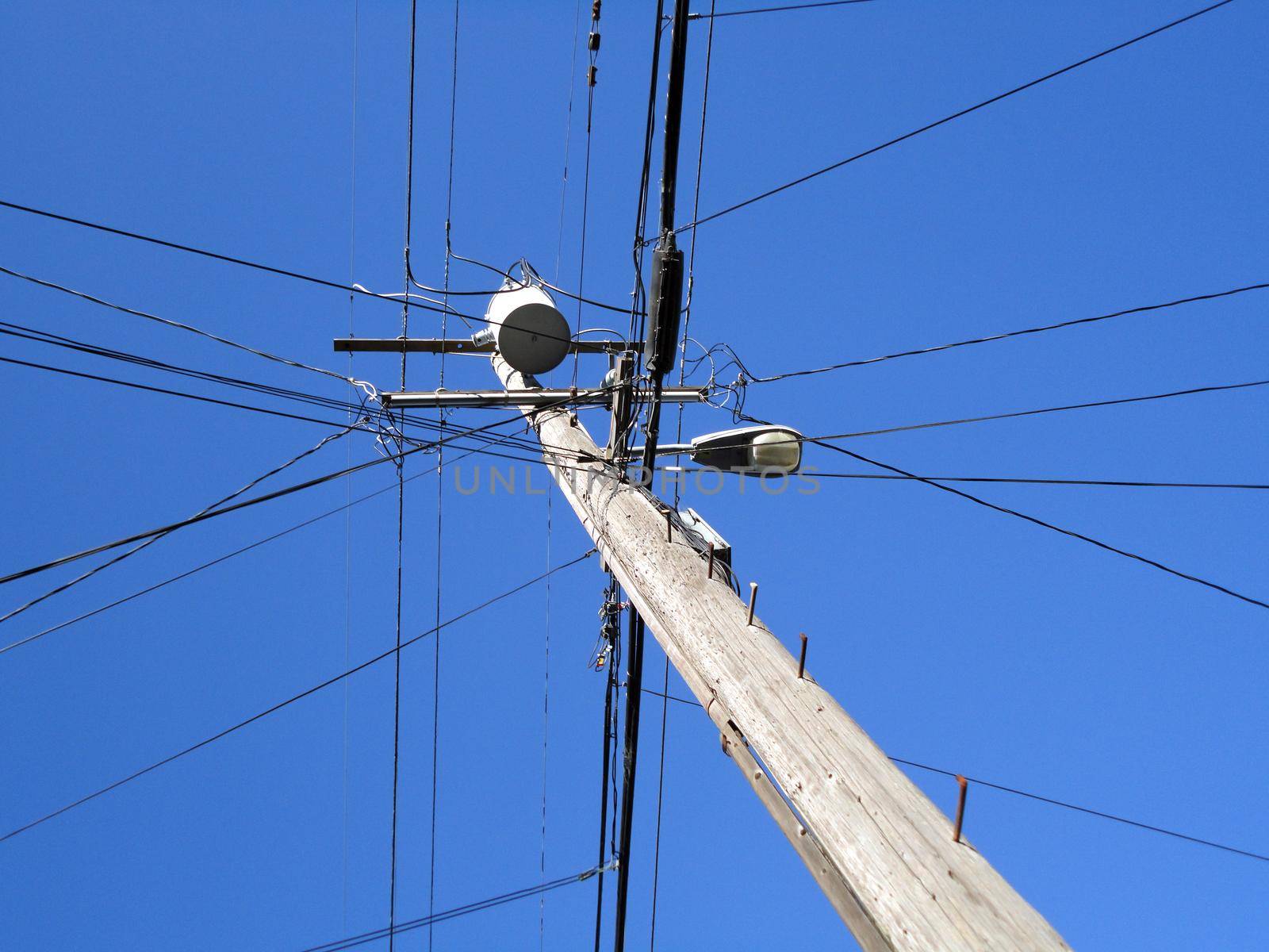 High Voltage Power Lines intersect at a wooden Utility pole with street light in Berkeley, California. 