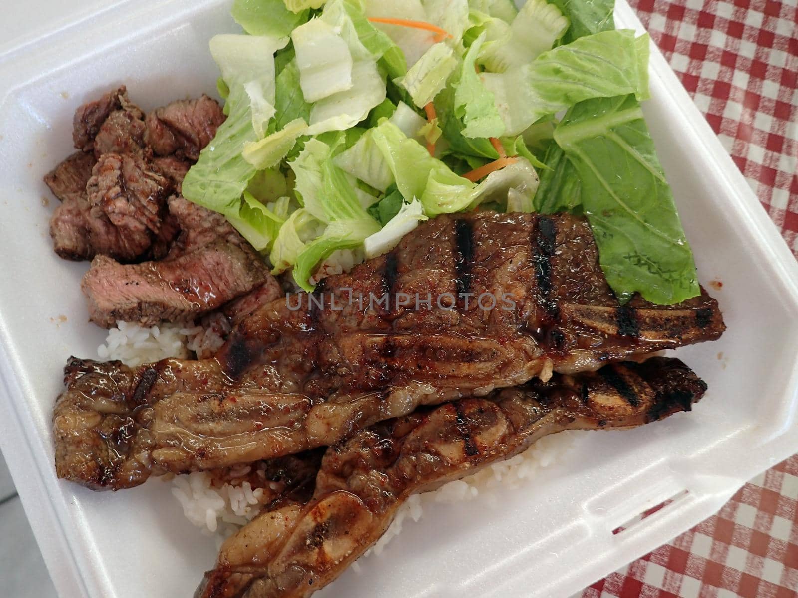 Steak, Kalbi, Side salad and white rice in a styrofoam plate. 