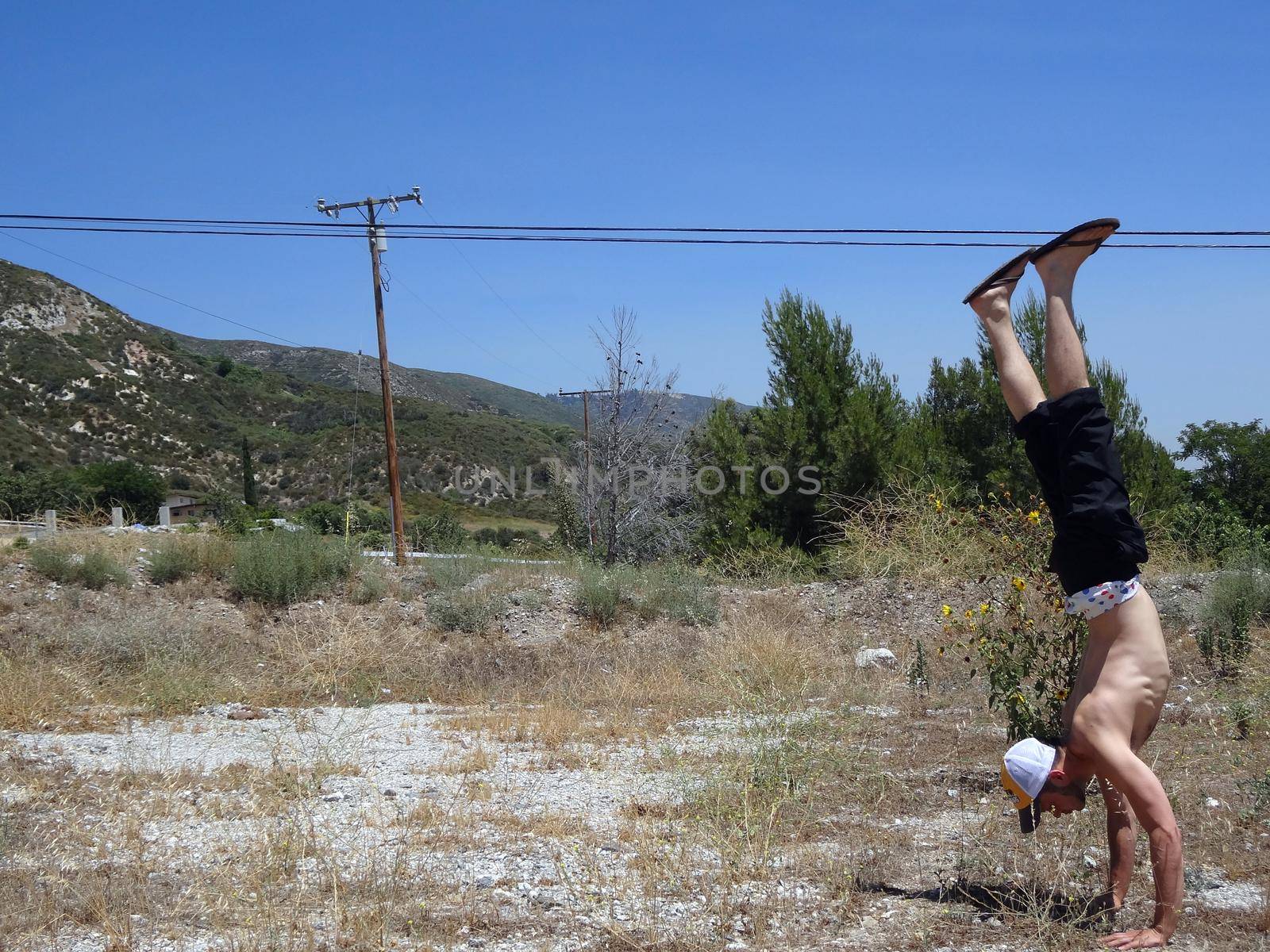 Handstanding in Dirt grass Field in California with powerlines and Mountain in the background.