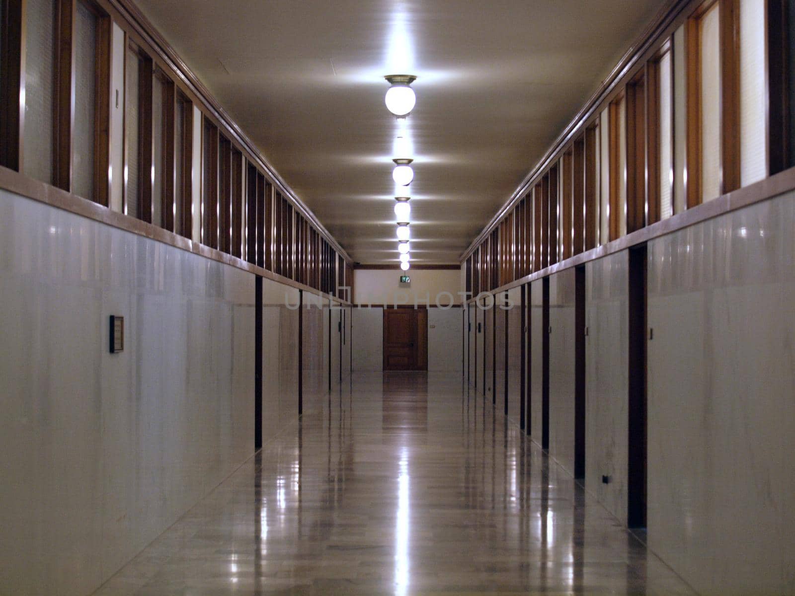 Long empty Hallway with doors in San Francisco City Hall with row of light overhead and granite walls.