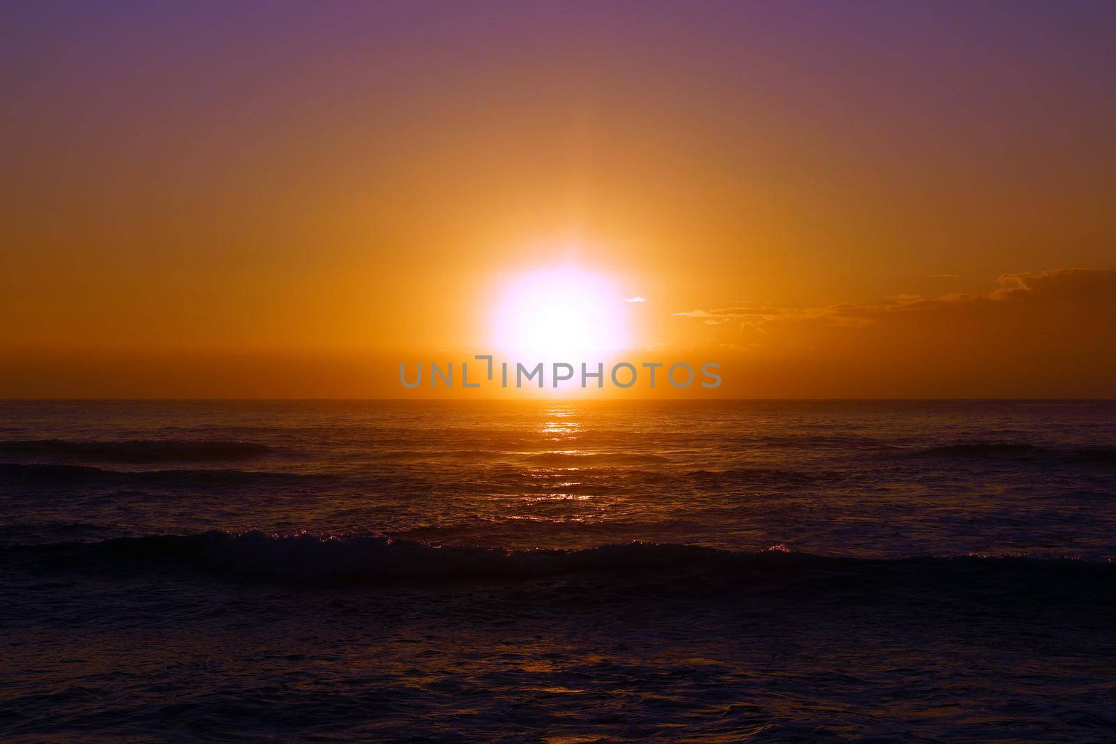 Spectacular Sunrise over the ocean with waves rolling toward shore in Hana on Maui, Hawaii.    