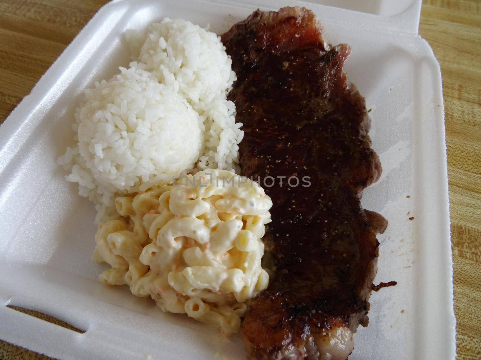 8 oz. Steak, White Rice, mac salad in a Styrofoam plate local Hawaiian style plate lunch.