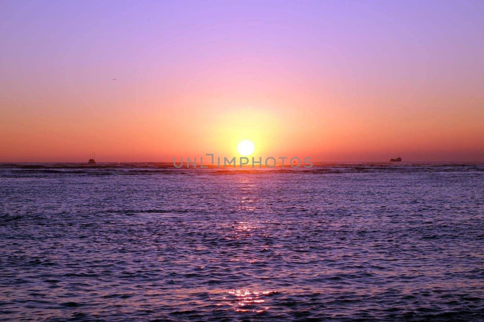 boats in the water during Sunset over the ocean at Ala Moana Beach Park on Oahu, Hawaii.