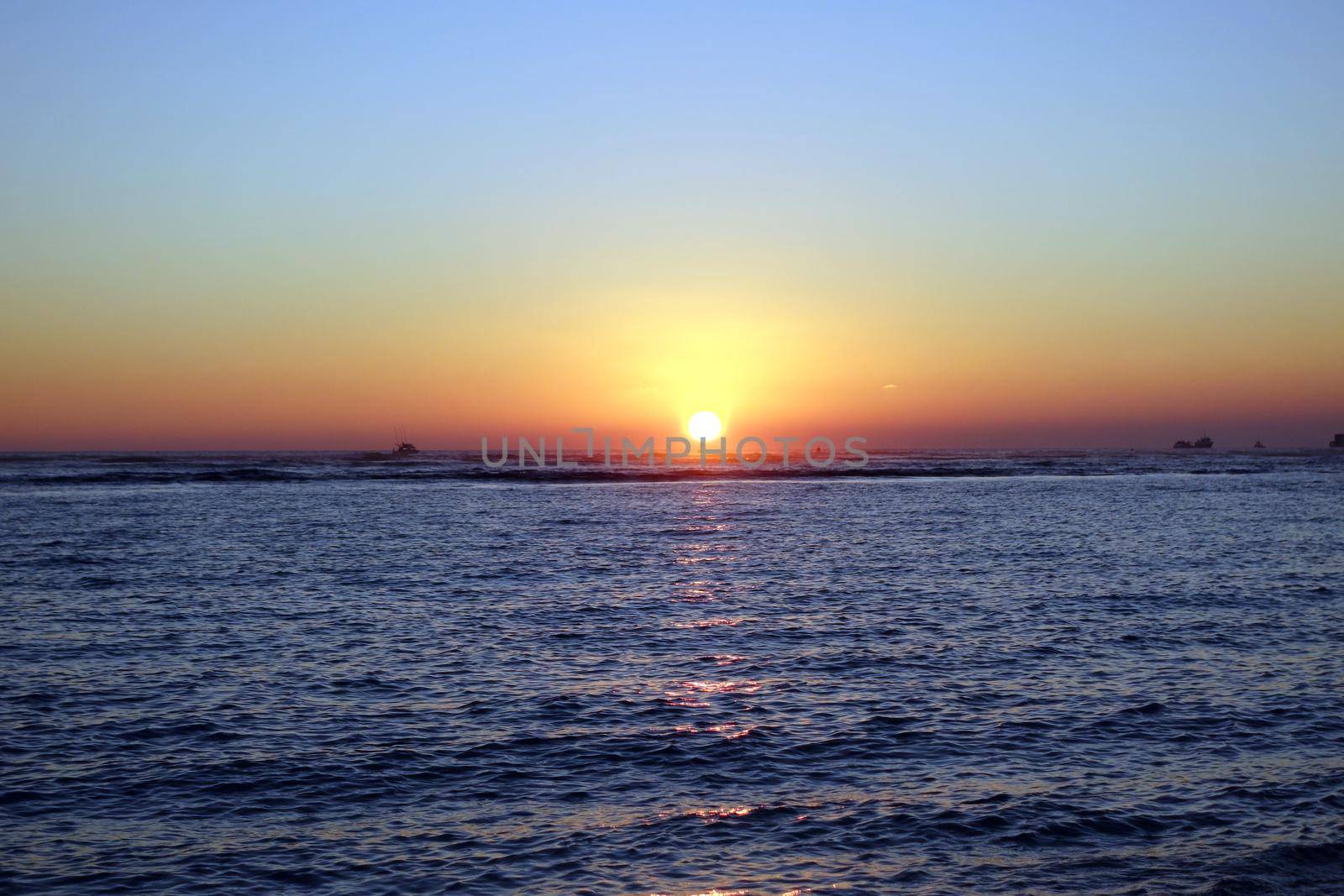 boats in the water during Sunset over the ocean at Ala Moana Beach Park on Oahu, Hawaii.