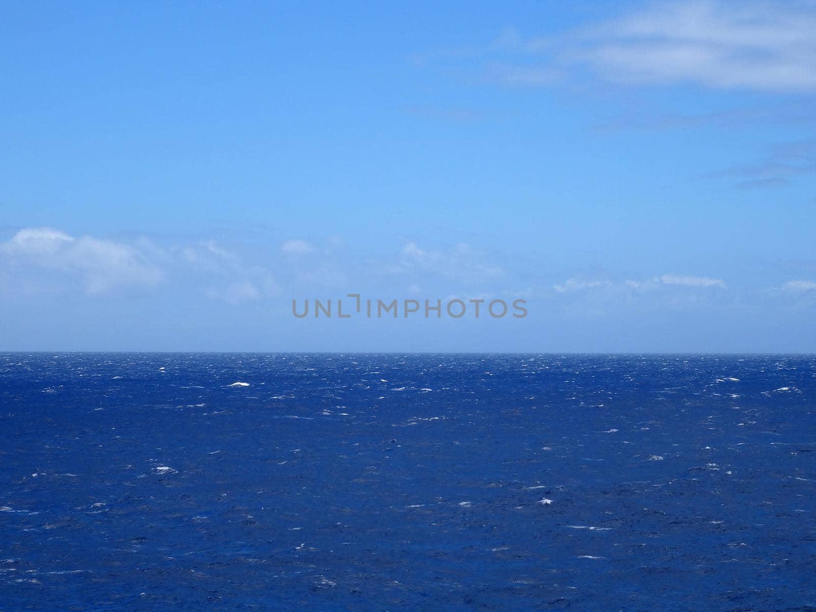 Shallow wavy ocean waters of east side of Oahu into the pacific ocean with a blue sky a few clouds in the state of Hawaii.