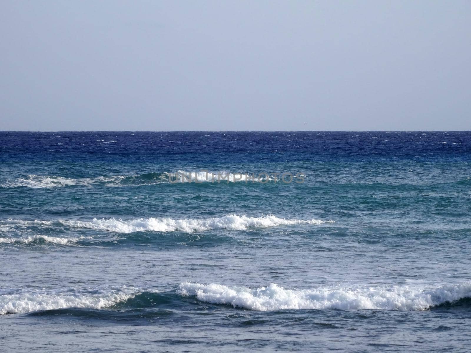 waves of the ocean break as they move towards shore in pacific ocean with a blue sky on Oahu.