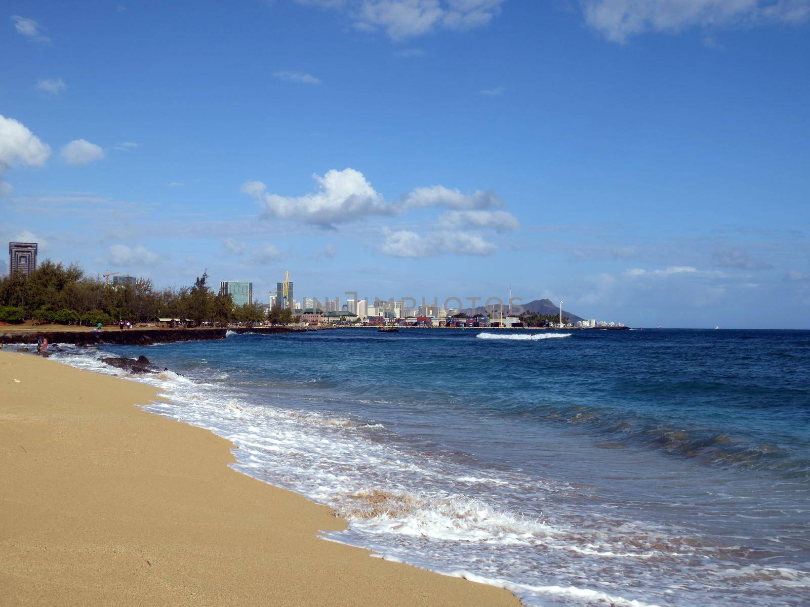 Sand Island Beach with Downtown Honolulu, Diamond head Crater in the distance on Oahu, Hawaii and waves lapping in the ocean.