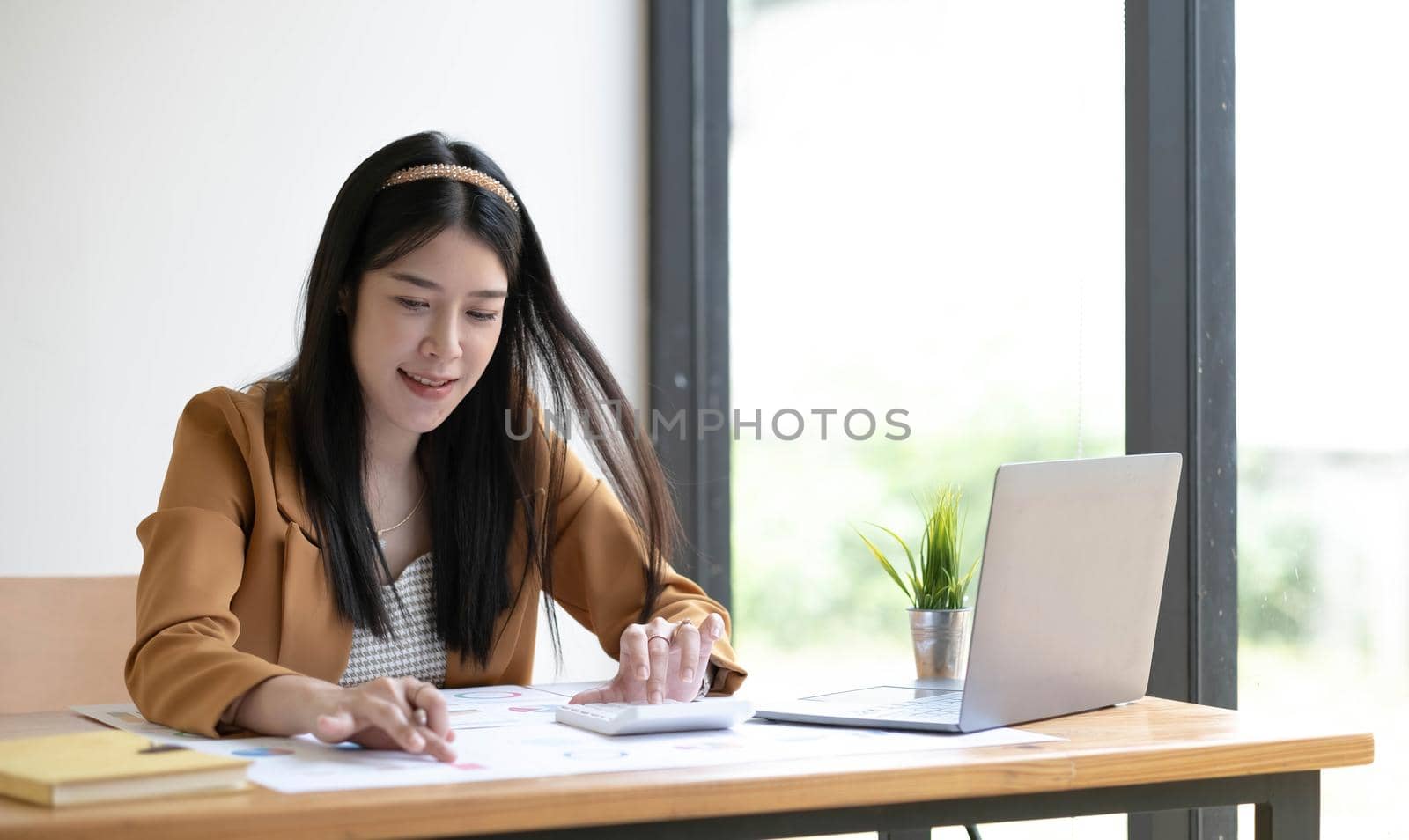 Portrait of asian business woman paying bills online with laptop in office. Beautiful girl with computer and chequebook, happy paying bills. Startup business financial calculate account concept.