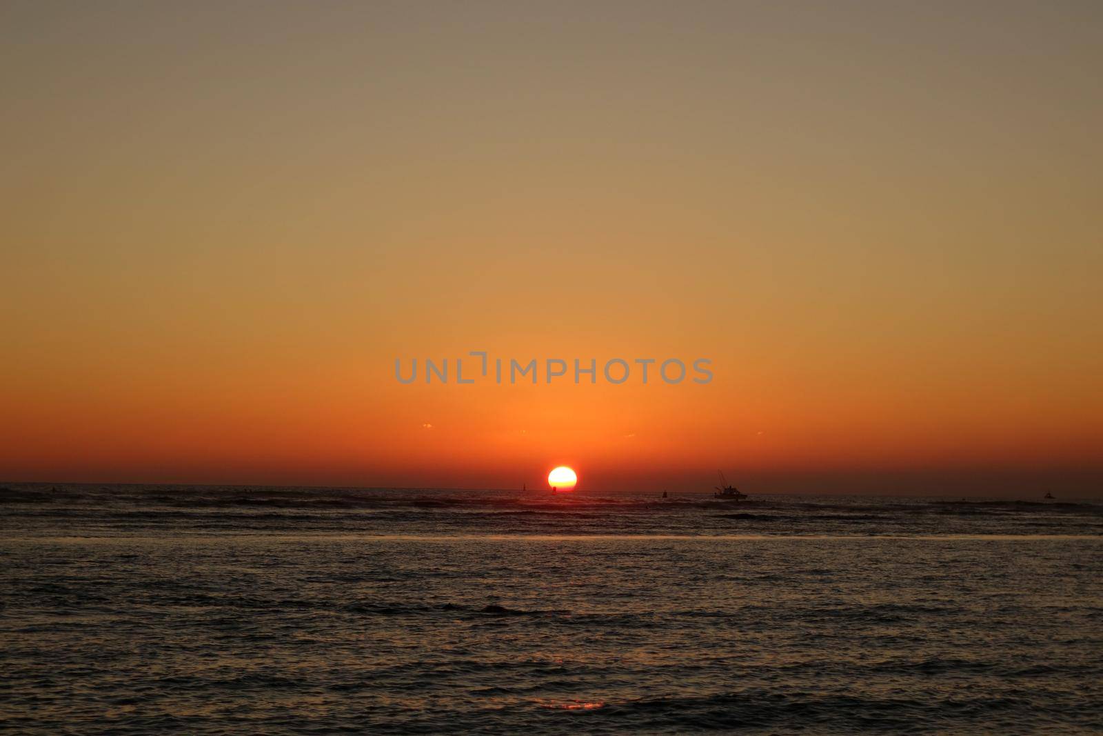 boats and buoy in the water during Sunset over the ocean at Ala Moana Beach Park on Oahu, Hawaii.