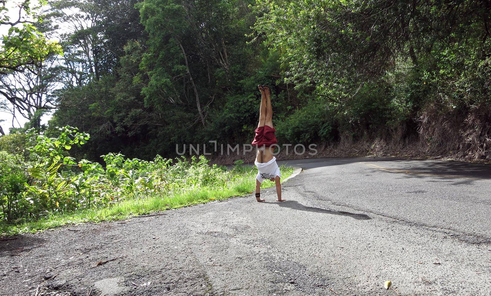 Man Handstands along curvy Mountain road with lush vegetation  by EricGBVD