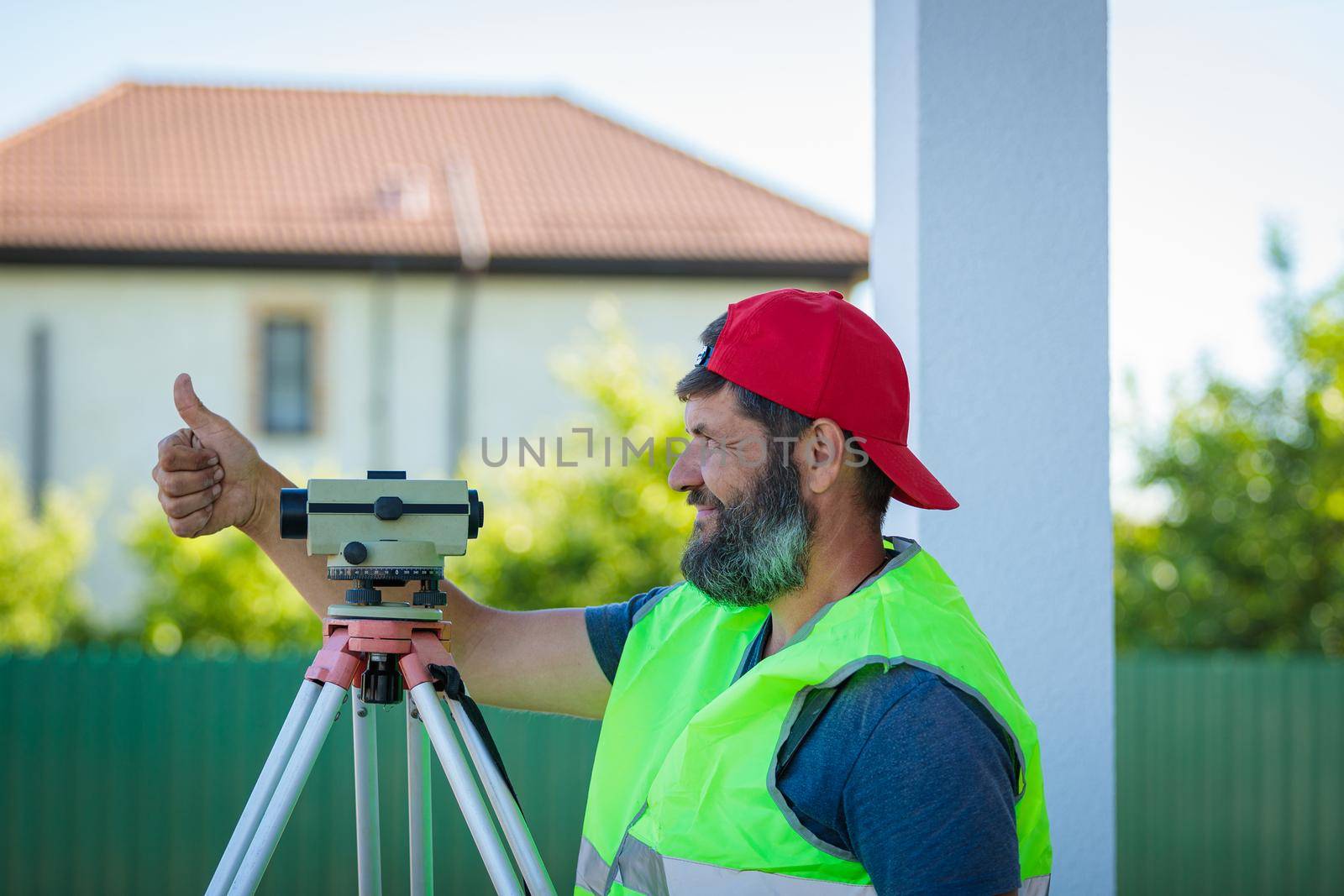 A man works with an optical level to level the landscape
