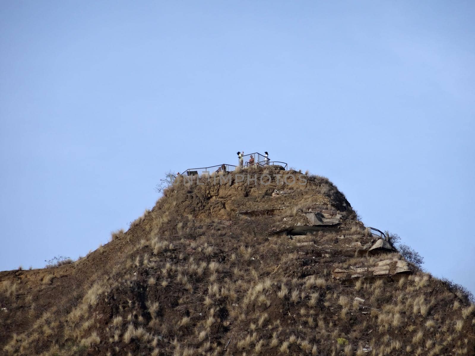 People take photos at Diamond Head Crater Lookout Peak with blue sky on Oahu, Hawaii.