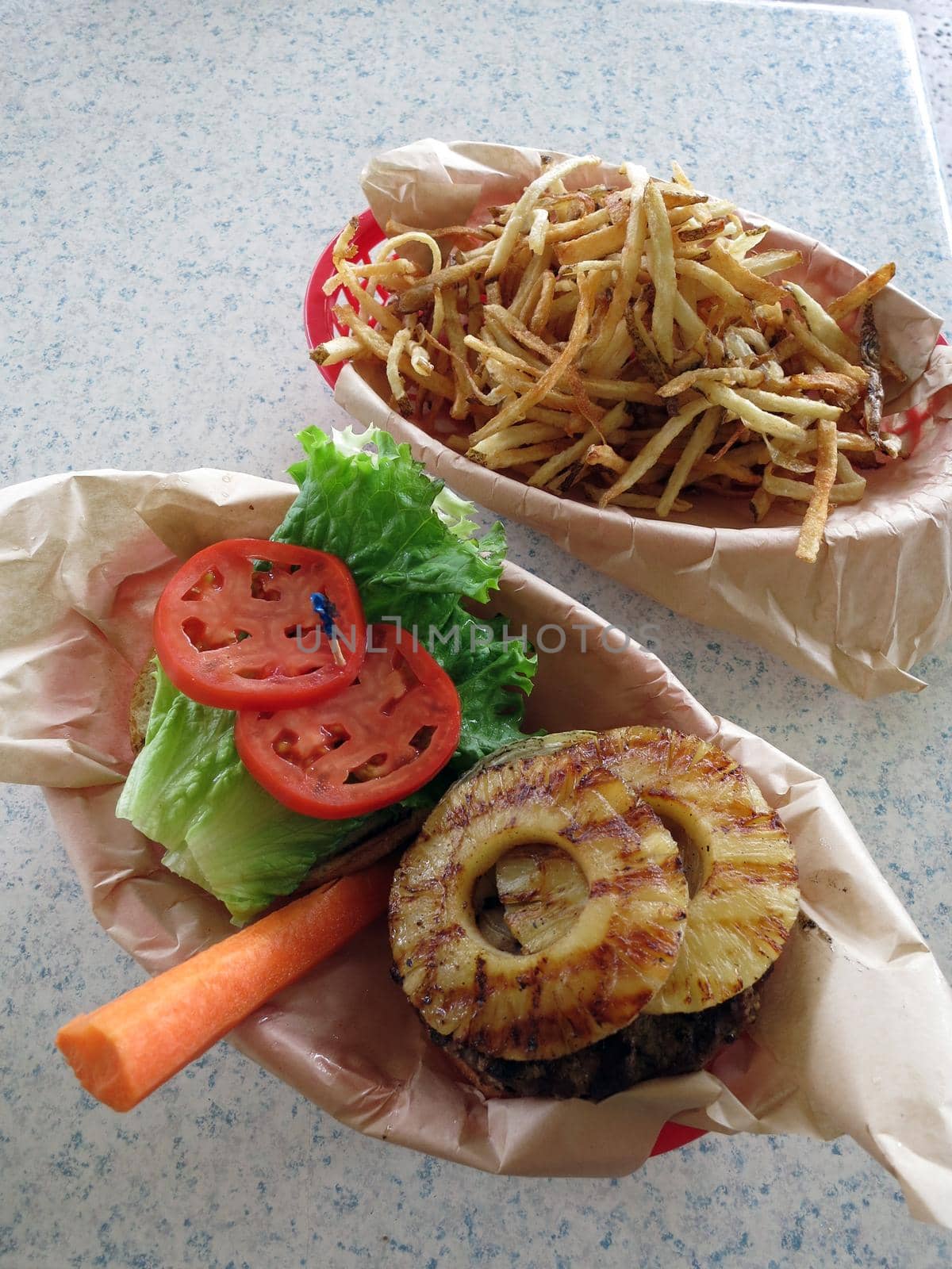 Open Face Hawaiian style burger with pineaple topping, lettuce, tomatoes, carrot with side of French fries.