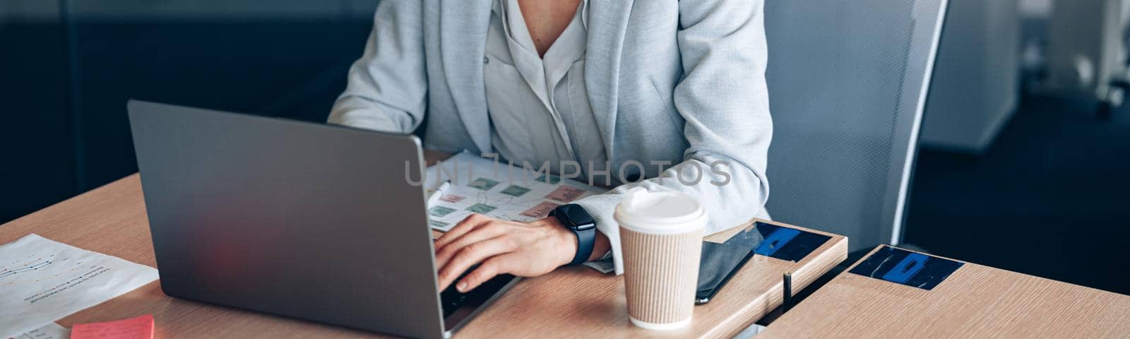 Portrait of smiling businesswoman working on laptop at her workplace at office. Blurred background.
