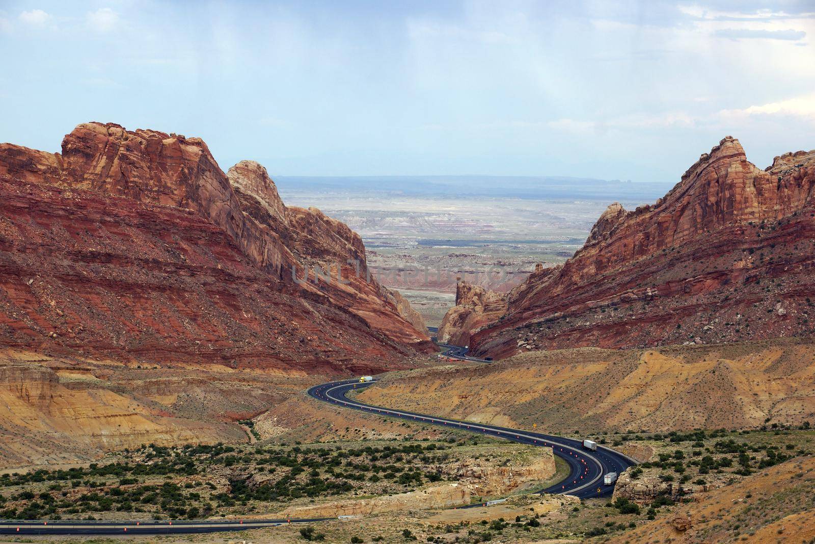Trucks drive along road that winds through Spotted Wolf Canyon in Utah, USA.