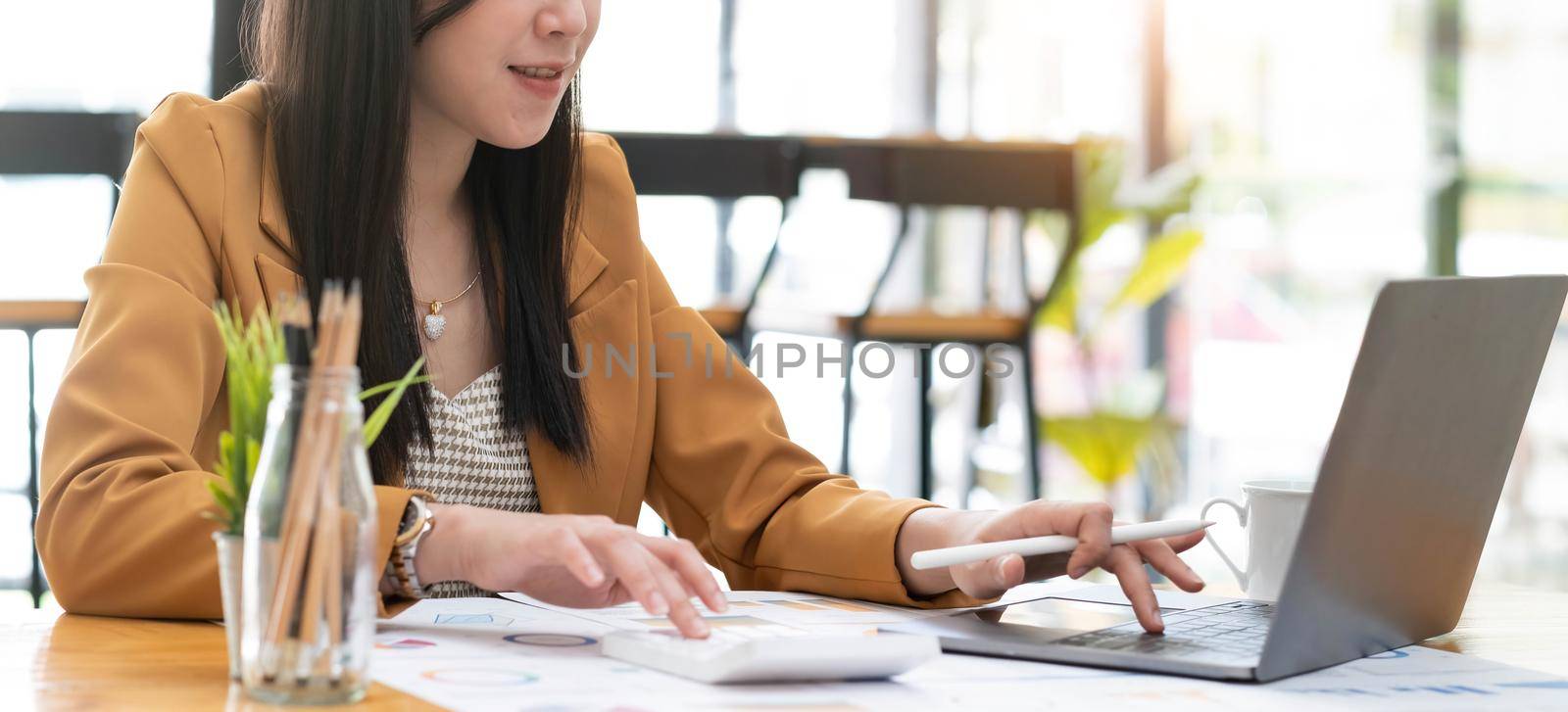 Business women using calculator at working with financial report. by wichayada